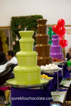 there is a large chocolate fountain in the middle of many other desserts on tables