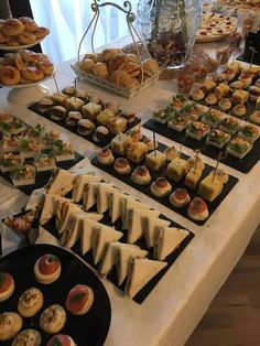 an assortment of appetizers are displayed on a table with white linens and black trays