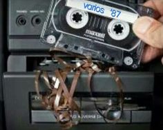 an old fashioned cassette tape recorder being held up by someone's hand and tied to it