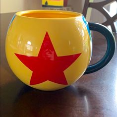 a yellow and red coffee cup sitting on top of a wooden table