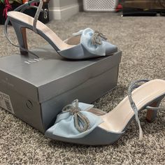 a pair of blue high heeled shoes sitting on top of a gray shoe box