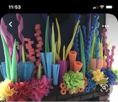 there are many different colored objects on the fireplace mantel, and one is made out of plastic straws