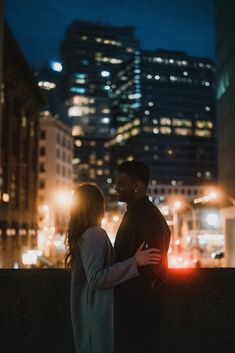 a man and woman standing next to each other in the city at night