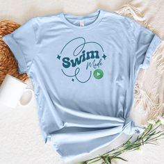 A graphic text t-shirt that reads Swim Mode with a power on button in a feminine style. Perfect for those who love swimming and want to showcase their love for the sport in a stylish way. This t-shirt is ideal for casual wear, active days at the pool or beach, and can also be a great gift for swimmers on birthdays, holidays, or other special occasions. This classic unisex jersey short sleeve tee fits like a well-loved favorite. Soft cotton and quality print make users fall in love with it over and over again. These t-shirts have-ribbed knit collars to bolster shaping. The shoulders are tapered for a better fit over time. Dual side seams hold the garment's shape for longer.   .: Made with 100% Airlume combed and ring-spun cotton, a lightweight fabric (4.2 oz/yd² (142 g/m that is easy to lay Gifts For Swimmers, Text T Shirt, Swimmers, Prism Color, Leisure Wear, Feminine Style, Jersey Shorts, Lightweight Fabric, Semi Formal