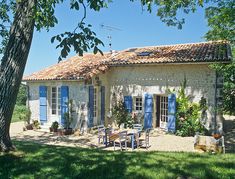 the house has blue shutters on it's windows, and is surrounded by trees