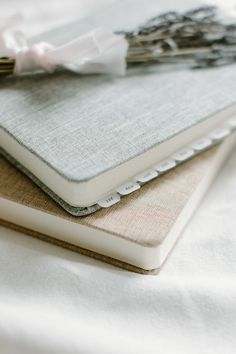 two notebooks sitting next to each other on top of a white bed sheet covered in sheets