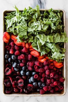 berries, strawberries and lettuce in a bowl on a marble counter top