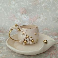 a white cup and saucer with beads on it