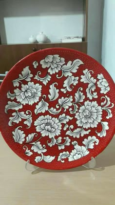 a red plate sitting on top of a wooden table next to a white and black flower