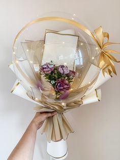 a person holding a bouquet of flowers in front of a white wall with lights on it