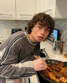 a young man is cooking some food on the stove