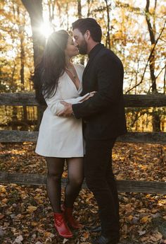 a man and woman standing next to each other in the leaves