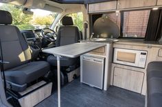 the interior of a van with an oven, sink and table in front of it