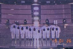 a group of men in white uniforms standing on a stage with an alarm clock behind them