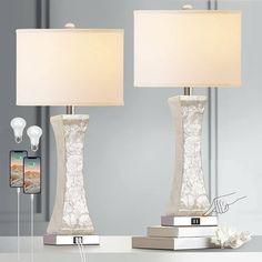 two lamps sitting on top of a table next to a phone and bookends