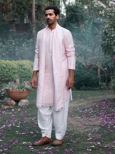 The jalalgarh kurta in powder pink is a charming and sophisticated choice for Indian grooms, ideal for haldi, mehndi, or sangeet ceremonies. Crafted from a luxurious blend of viscose cotton silk and georgette, this kurta offers a smooth and breathable feel, perfect for long celebrations. The kurta comes with an ivory salwar, creating a balanced and harmonious ensemble. The jalalgarh kurta is perfect for grooms who want a contemporary yet traditional outfit. Pair it with traditional juttis or modern footwear for a polished and sophisticated appearance. Pink Kurta, Traditional Outfit, Indian Groom, Bespoke Tailoring, Kurta Set, Powder Pink, Personal Shopper, Cotton Silk, Traditional Outfits