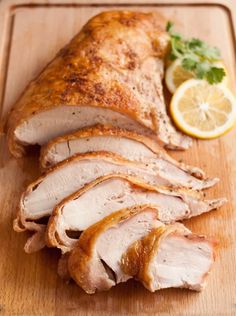 sliced pork on a cutting board with lemons and parsley next to the meat