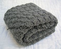 two gray crocheted blankets sitting on top of a white bed sheet with the words jane's close knitters written across it