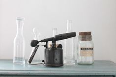 an old fashioned hair dryer sitting on top of a table next to glass bottles