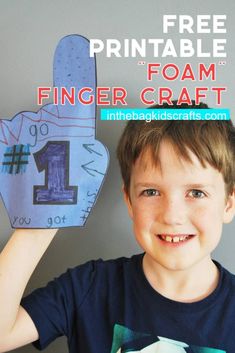 a young boy holding up a paper finger craft