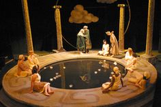 a group of people sitting on top of a round table in front of a pond