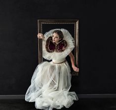 a woman in a white dress is posing for a photo with her hands behind her head