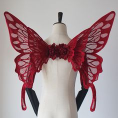 a white mannequin with red wings and flowers on it's headpiece