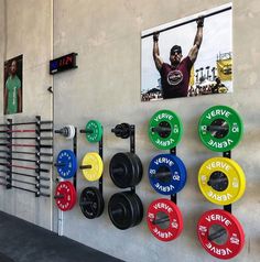 there are many different colored barbells hanging on the wall