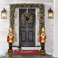 two christmas nutcrackers standing in front of a door decorated with garland and lights