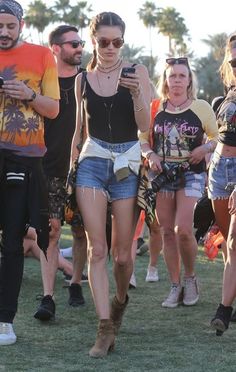 a group of people walking down a grass covered field next to each other with cell phones in their hands