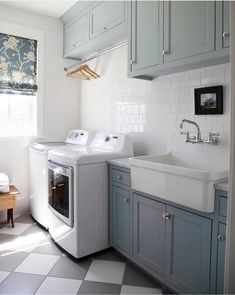 a washer and dryer sitting in a kitchen next to a window with blue cabinets