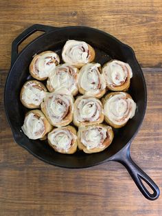 a pan filled with cinnamon rolls on top of a wooden table