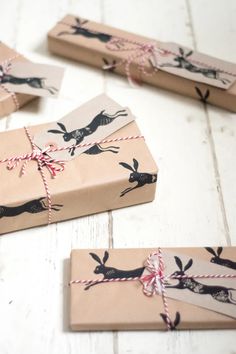 several wrapped presents tied with twine on white wooden floored area, including one brown paper bag and two black deer designs