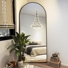 a bedroom with a large mirror on the wall next to a potted plant and books