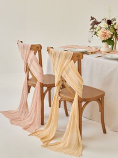 the table is set with two wooden chairs and one chair has a sheer fabric draped over it