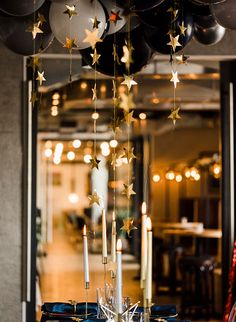 the table is set with black and white plates, silverware, and star - shaped balloons