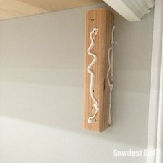 a wooden shelf hanging from the ceiling with white paint on it and some wires attached to it