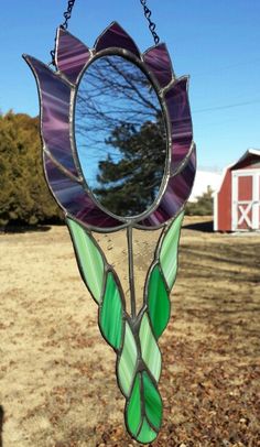 a stained glass sun catcher hanging in front of a red barn with a blue sky