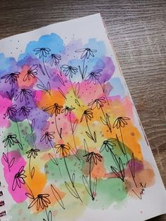 an art journal with watercolors and ink on paper, featuring flowers in the middle