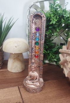 a statue with seven chakras sitting on top of a wooden table next to some plants