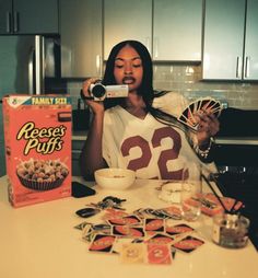 a woman holding up a camera in front of a box of cereal and cupcakes