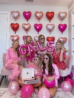 a group of women posing for a photo with pink balloons and heart shaped balloons on the wall