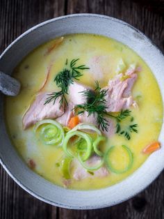 a bowl of soup with meat and vegetables in it on top of a wooden table