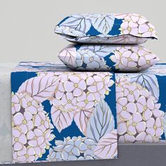 three pillows are stacked on top of each other with blue and pink floral designs in the background