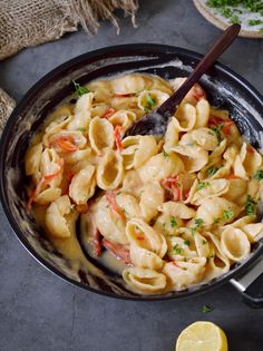 a skillet filled with pasta and garnished with parsley on the side