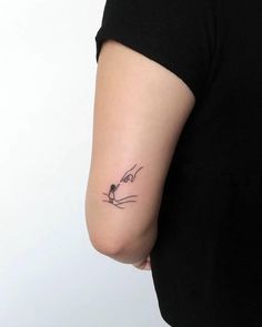 a woman's arm with a small cat tattoo on the left side of her arm