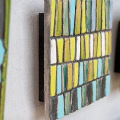 a close up of a wall mounted art piece with multicolored tiles on it