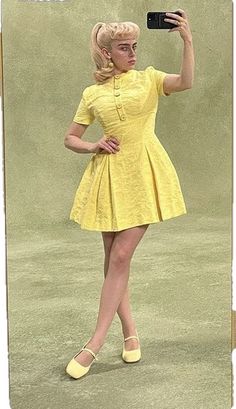 a woman in a yellow dress taking a selfie