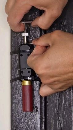 two hands are opening a door with a small red lighter attached to the handle on it