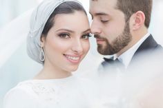 a bride and groom are posing for a wedding photo with veil blowing in the wind